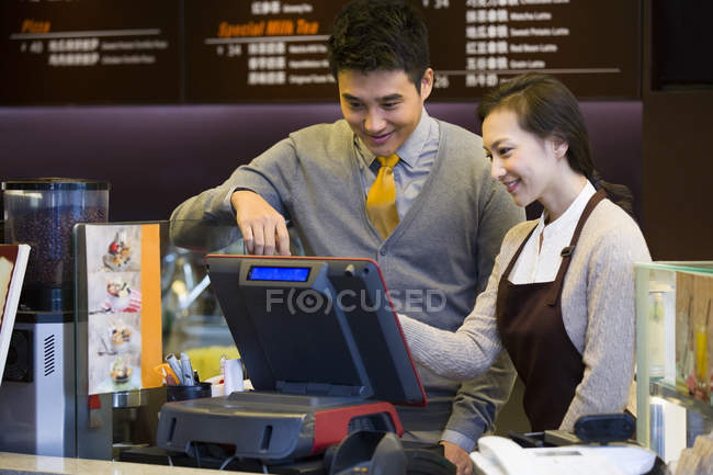 Cafetería china tendero y camarera usando caja registradora - foto de stock