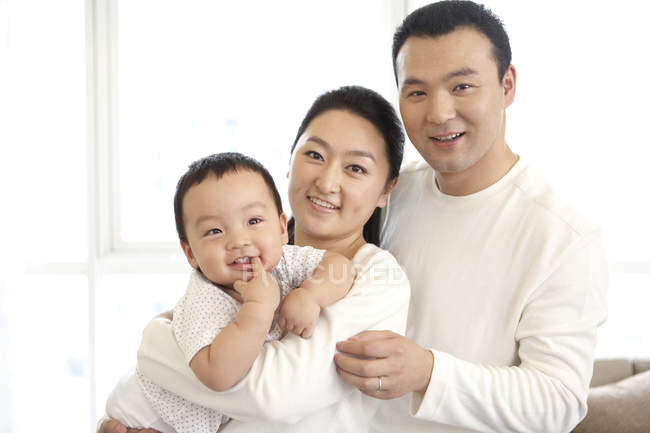 Padres chinos sosteniendo bebé hijo - foto de stock