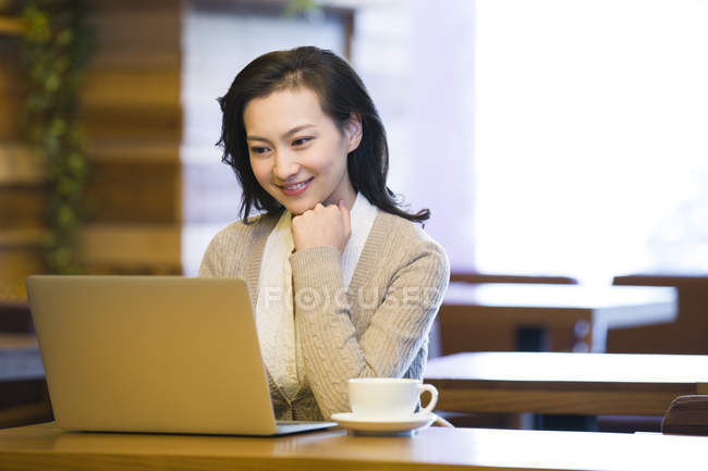 Китаянка с ноутбуком в кафе — стоковое фото