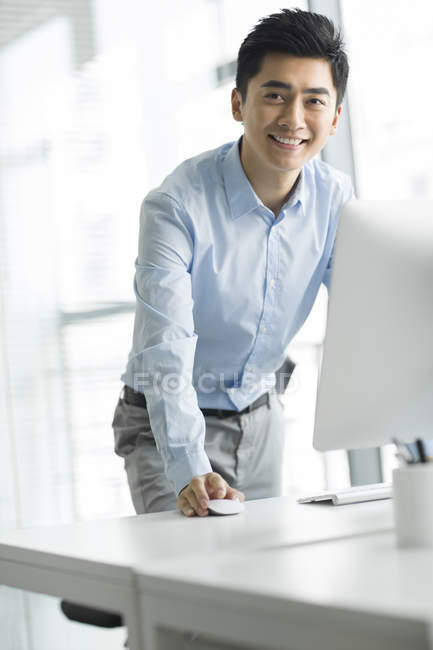 Homem de negócios chinês em pé no computador no escritório — Fotografia de Stock