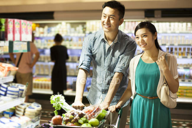 Chinese couple shopping in supermarket with cart — Stock Photo