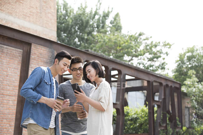 Chinese friends using smartphone at street — Stock Photo