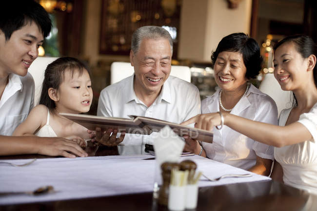 Китайская семья нескольких поколений просматривает меню в ресторане — стоковое фото