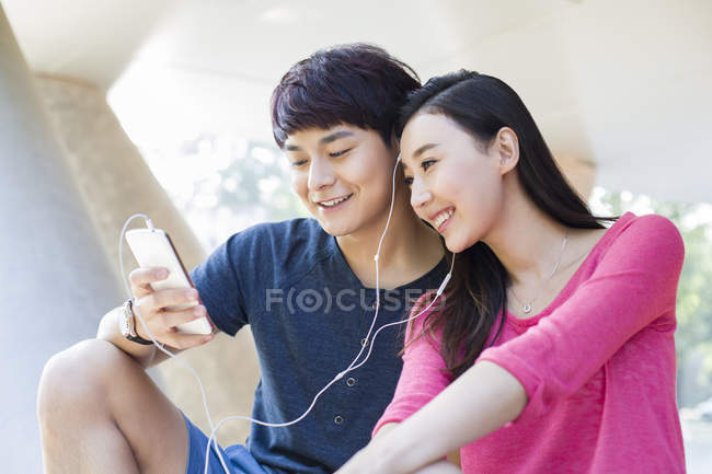 Casal chinês ouvindo música no smartphone juntos — Fotografia de Stock