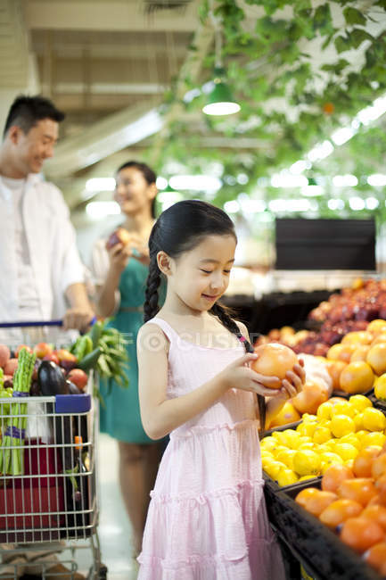 Китайська дівчина з батьками, купуючи фрукти в супермаркеті — стокове фото
