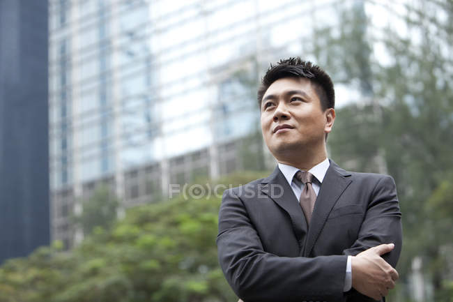 Chinese businessman with arms crossed on street — Stock Photo