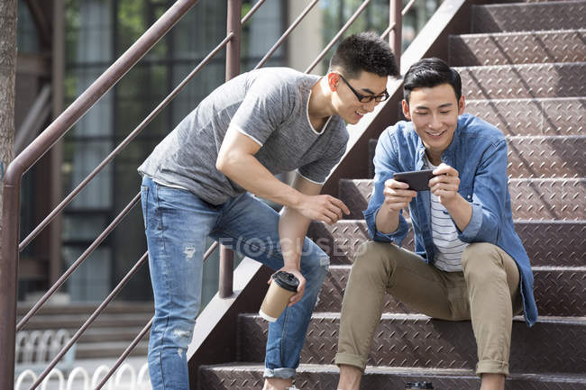 Amigos chinos usando smartphone en la calle - foto de stock