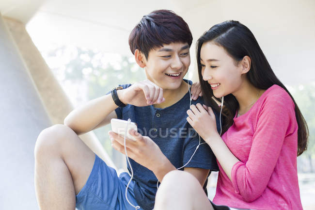 Китайська пара, прослуховування музики на смартфоні разом — стокове фото