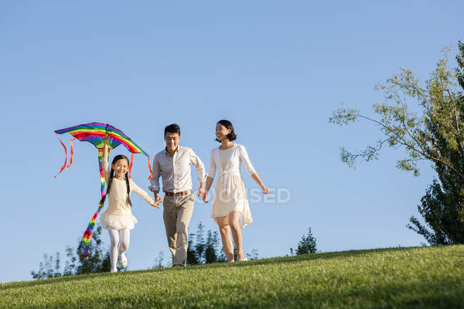 Pais chineses com filha voando pipa no parque — Fotografia de Stock