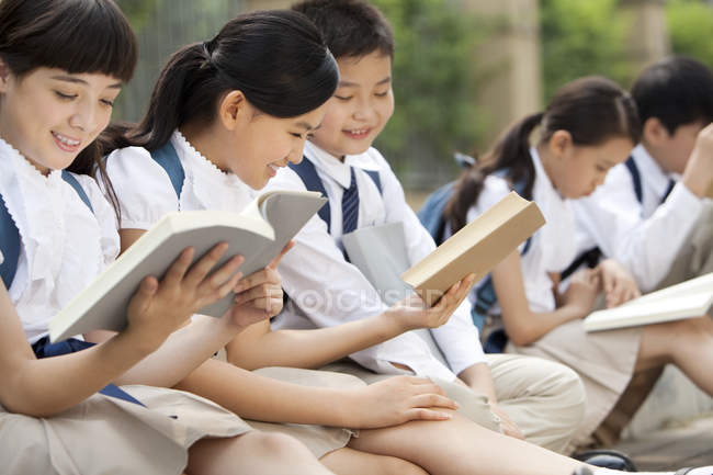 Chinese schoolchildren reading books at school yard — Stock Photo