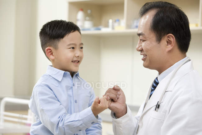 Chino y médico haciendo promesa meñique - foto de stock