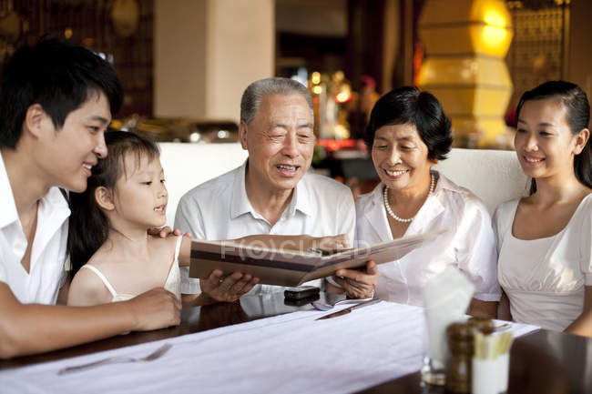 Familia multi-generación china mirando a través del menú en el restaurante - foto de stock