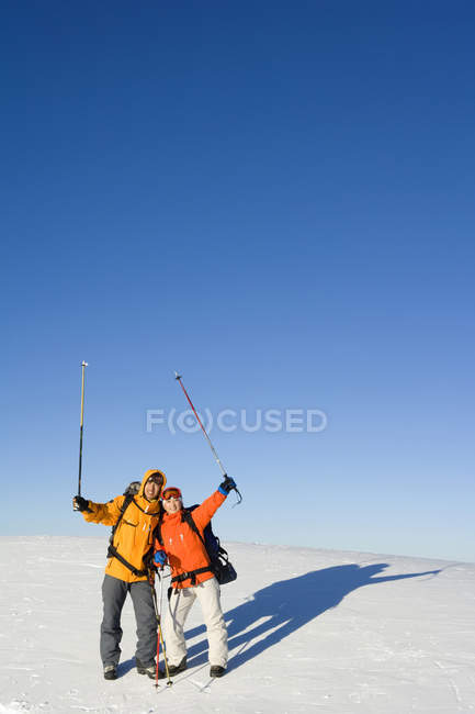 Pareja china posando con bastones de esquí en el aire - foto de stock