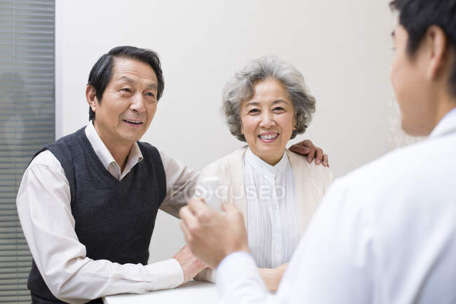 Médico chino explicando la dosis de la medicina a la pareja mayor - foto de stock