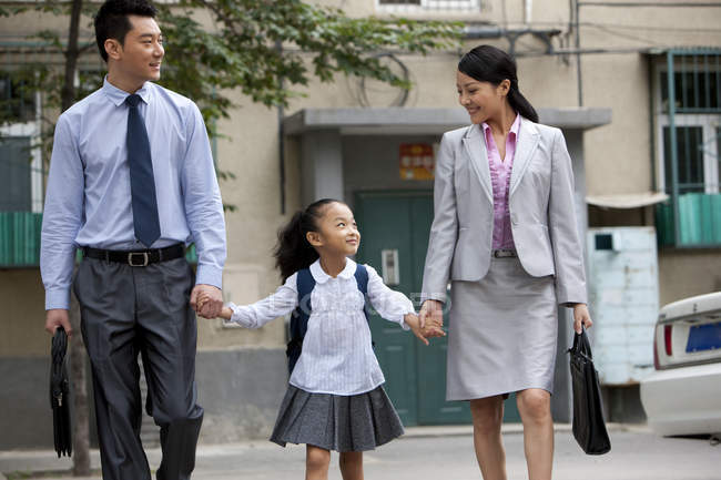 Chinese schoolgirl walking with parents on street — Stock Photo