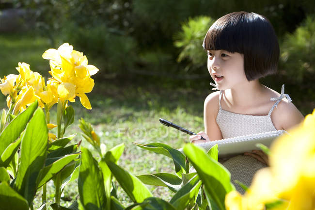 Pequena menina chinesa desenho flores amarelas no jardim — Fotografia de Stock