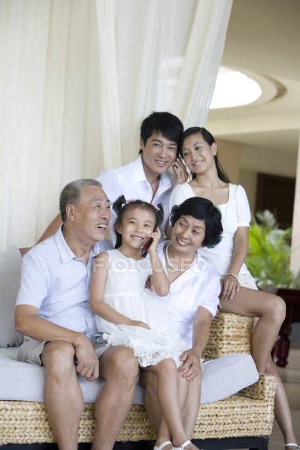 Famiglia cinese seduta sulla panchina in hotel mentre la ragazza parla al telefono — Foto stock
