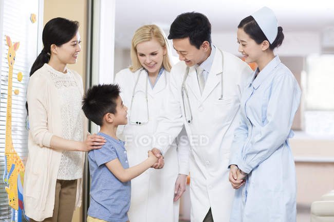 Médico chino y niño estrechando las manos - foto de stock