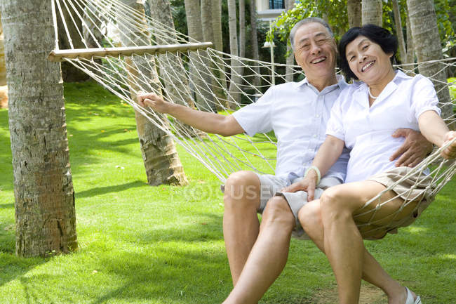 Senior Chinese couple relaxing in hammock on vacation — Stock Photo