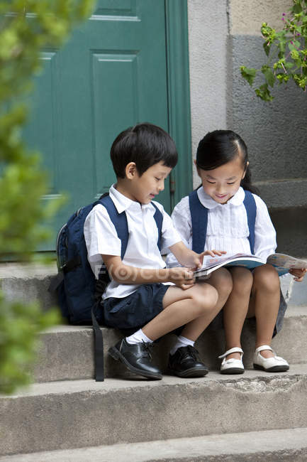 Chinese boy and girl studying on porch — Stock Photo