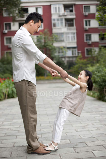 Chinesischer Vater und Tochter beim Spielen und Händchenhalten im Garten — Stockfoto