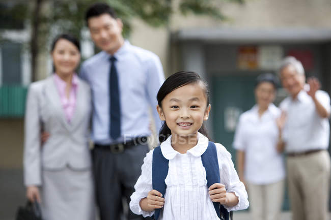 Chinese schoolgirl with family in background — Stock Photo