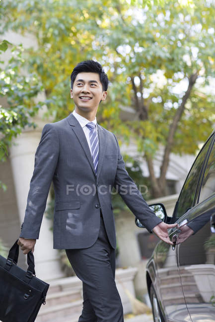 Junger chinesischer Geschäftsmann öffnet Autotür — Stockfoto