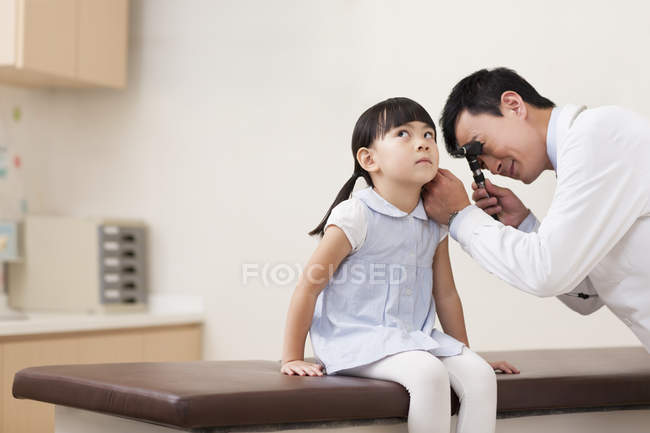 Chinese doctor examining girl ear — Stock Photo