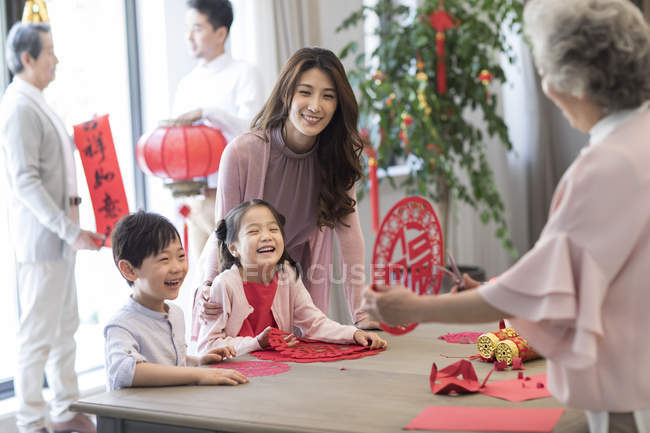 Abuela con los niños y la madre haciendo chino de Año Nuevo papel de corte - foto de stock