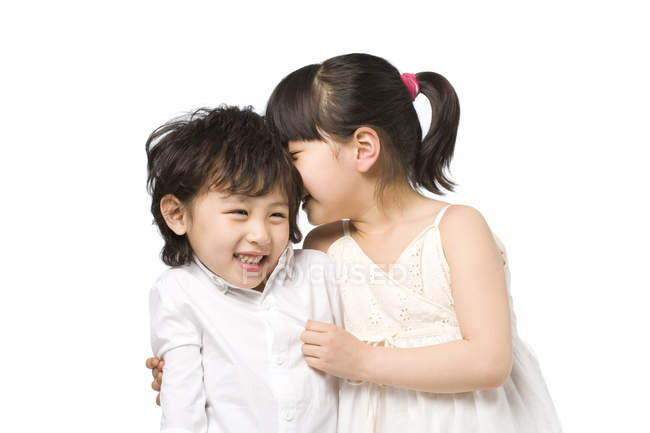 Asiático irmãos sussurrando e sorrindo no fundo branco — Fotografia de Stock