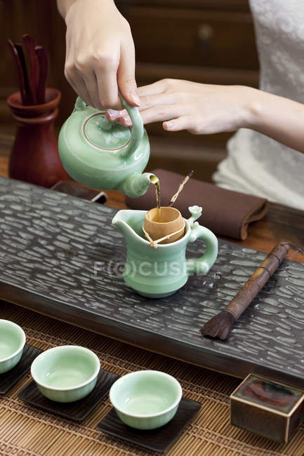 Gros plan des mains féminines versant du thé dans la bouilloire — Photo de stock