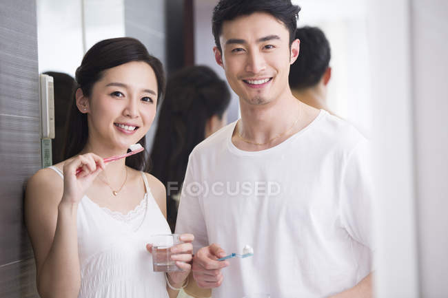Chinese couple brushing teeth in bathroom — Stock Photo