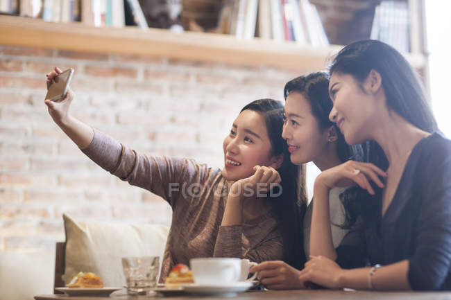 Chinese female friends taking selfie in coffee shop — Stock Photo
