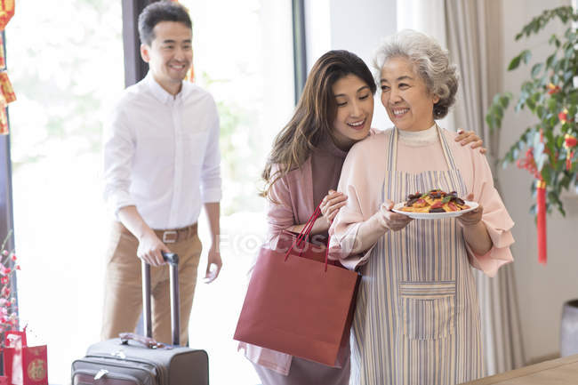 Young couple visiting senior woman with food during Chinese new year — Stock Photo