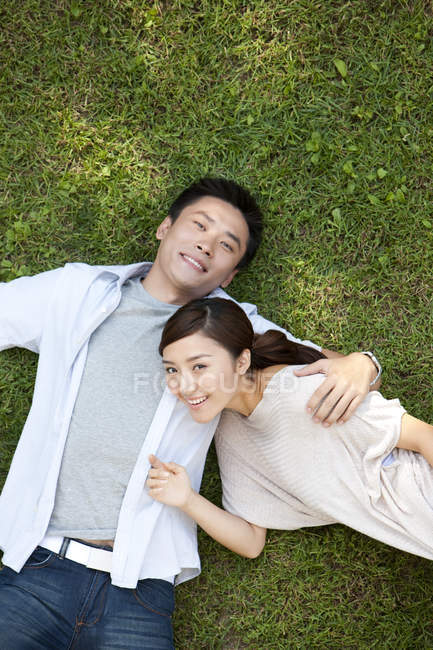 Vista aérea de la joven pareja china acostada en la hierba - foto de stock