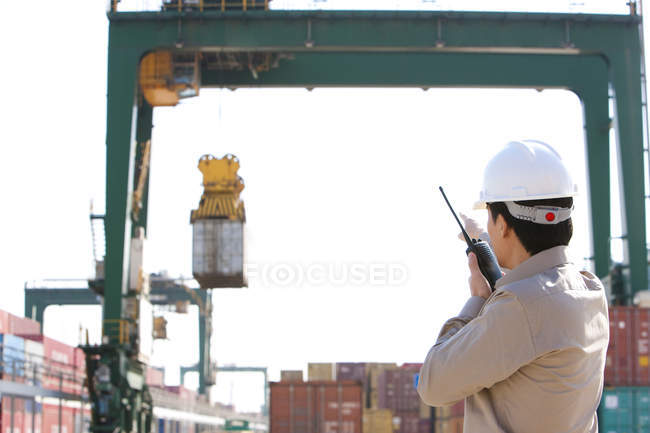 Trabalhador da indústria naval chinesa dirigindo guindaste com walkie-talkie — Fotografia de Stock