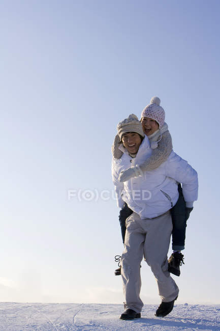 Uomo cinese che trasporta donna a cavalluccio sulla neve — Foto stock