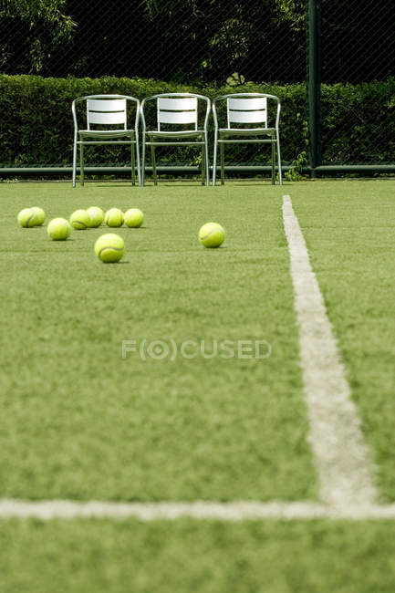 Tennis balls on green practice court — Stock Photo