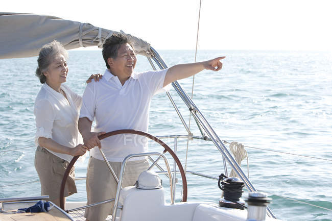 Senior Chinese couple sailing and pointing at view — Stock Photo