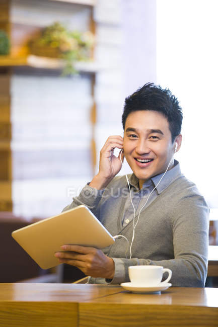 Chinese man music in digital tablet in coffee shop — Stock Photo