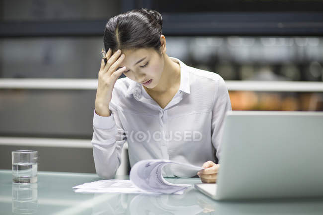 Втомився китайський бізнес-леді працює з документи в офісі — стокове фото