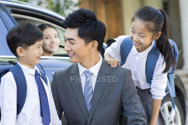 Chinese father and siblings talking in front of car with mother — Stock Photo