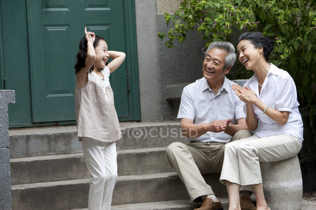 Chinese elementary age girl playing with grandparents on street — Stock Photo