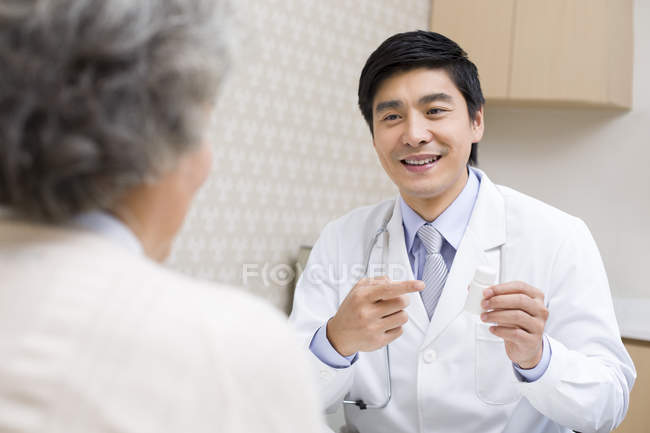 Китайский врач объясняет пациенту дозировку лекарств — стоковое фото