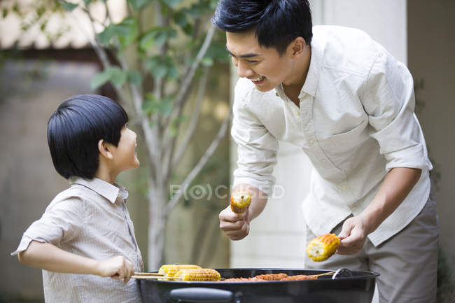 Père et fils chinois barbecuant dans la cour — Photo de stock