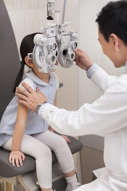 Chinese doctor examining girl eyes — Stock Photo