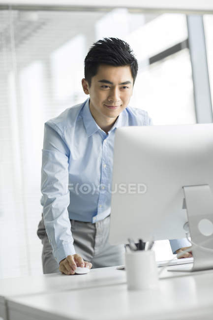 Hombre de negocios chino usando la computadora en la oficina - foto de stock
