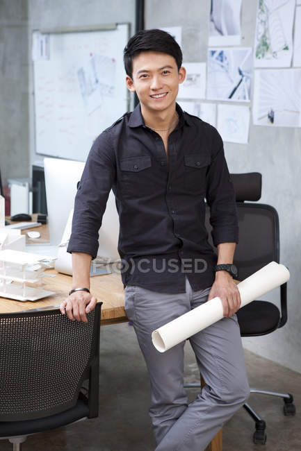 Architetto cinese maschio in possesso di cianografia in ufficio — Foto stock