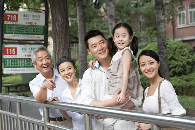 Familia china con hija esperando en parada de autobús - foto de stock
