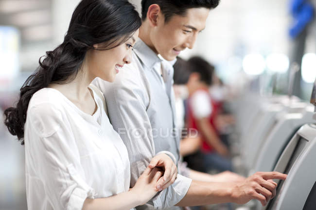 Couple chinois utilisant la billetterie à l'aéroport — Photo de stock